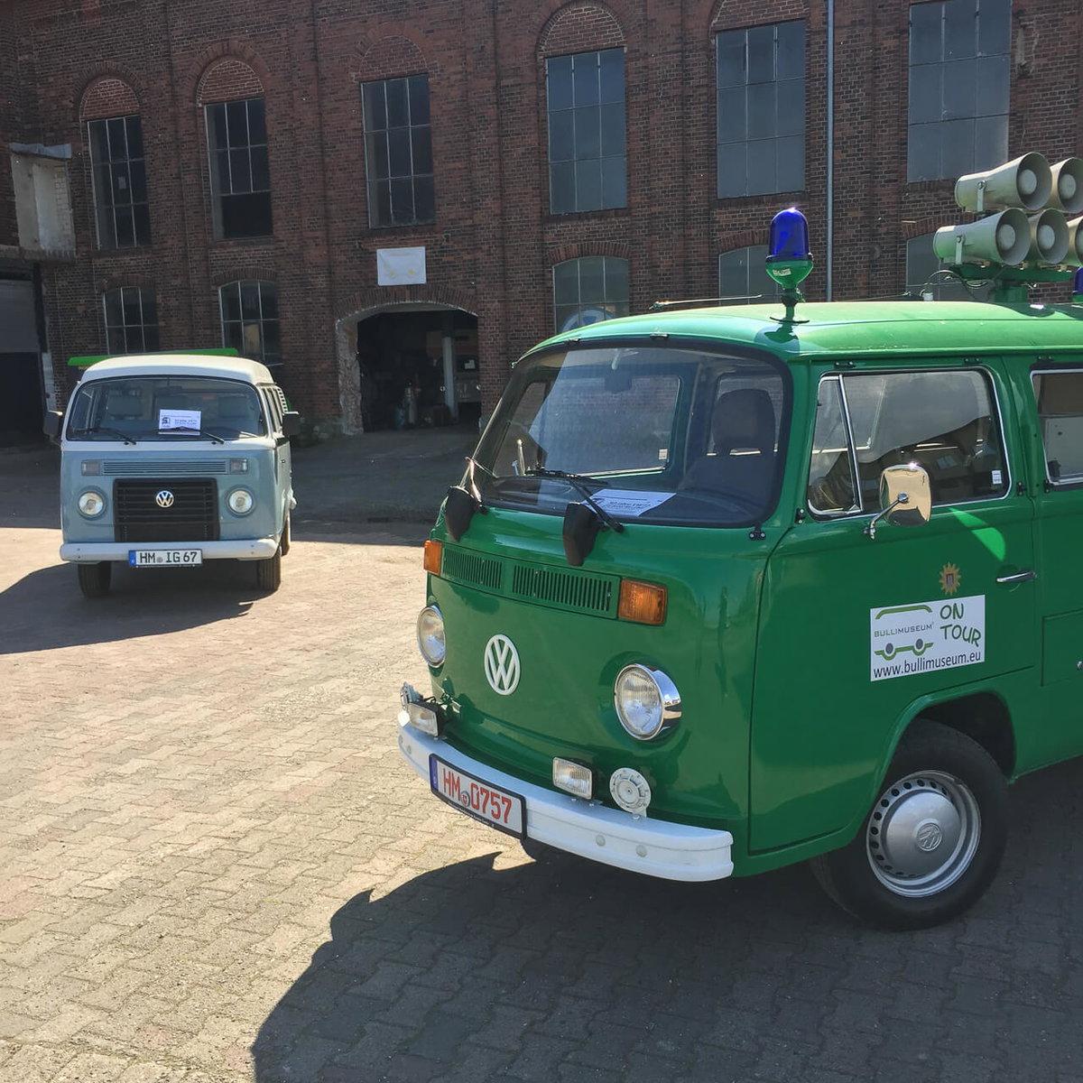 Zwei VW Bullis auf einem Hof