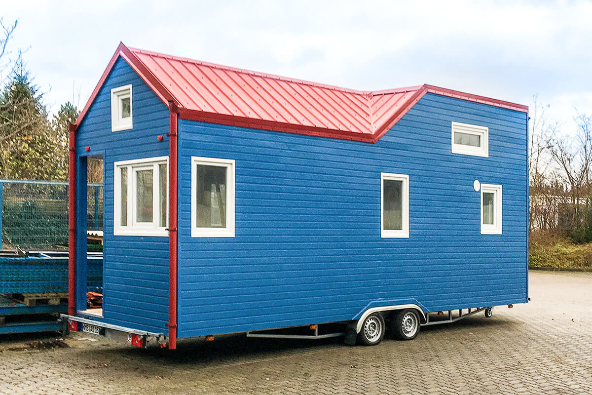 Blaues Tiny House aus Holz mit rotem Dach