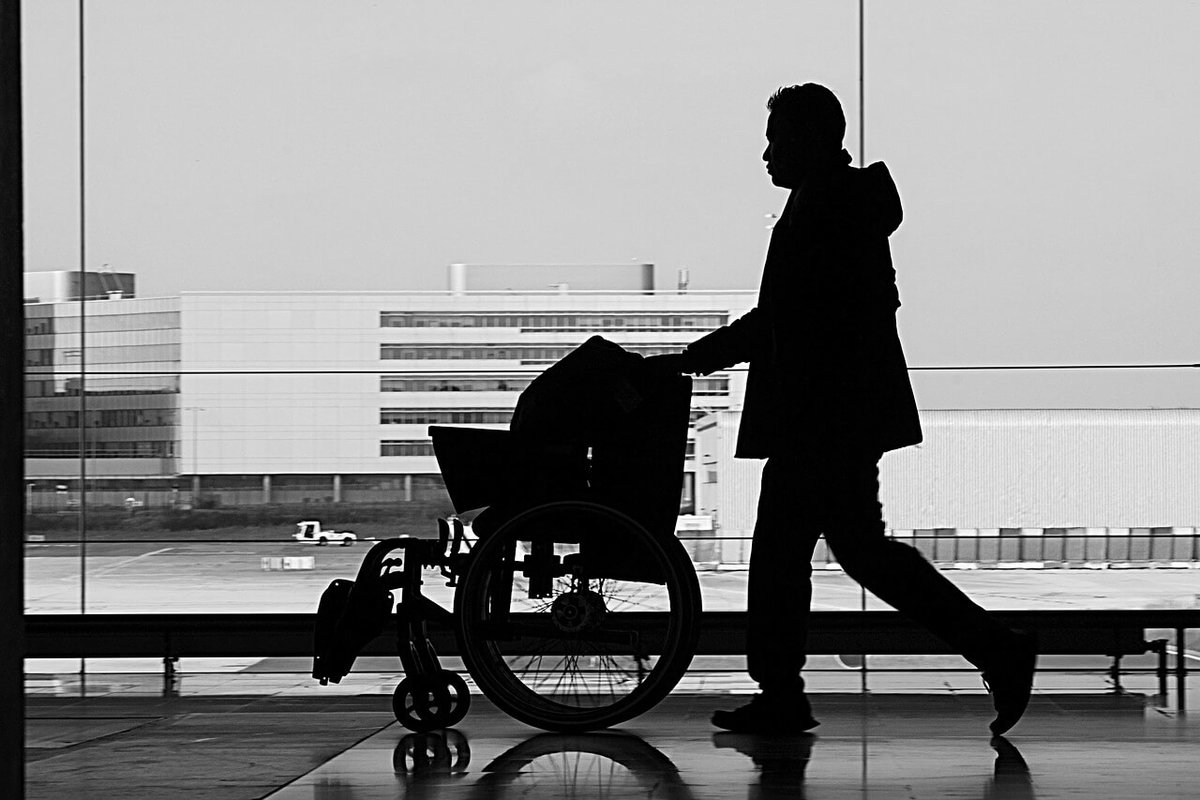 Mann schiebt einen Rollstuhl am Flughafen
