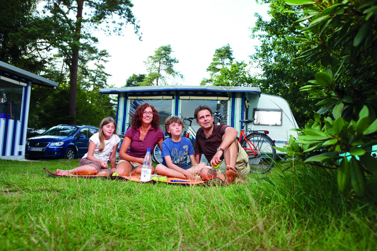 Eine Familie vor ihrem Camper auf dem Suedsee Campingplatz einem Luxuscampingplatz in Deutschland