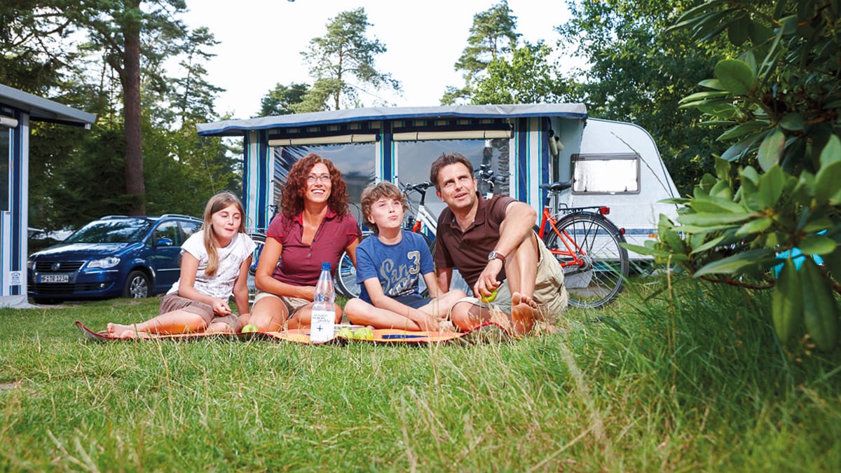 Eine Familie vor dem Camper auf dem Campingplatz