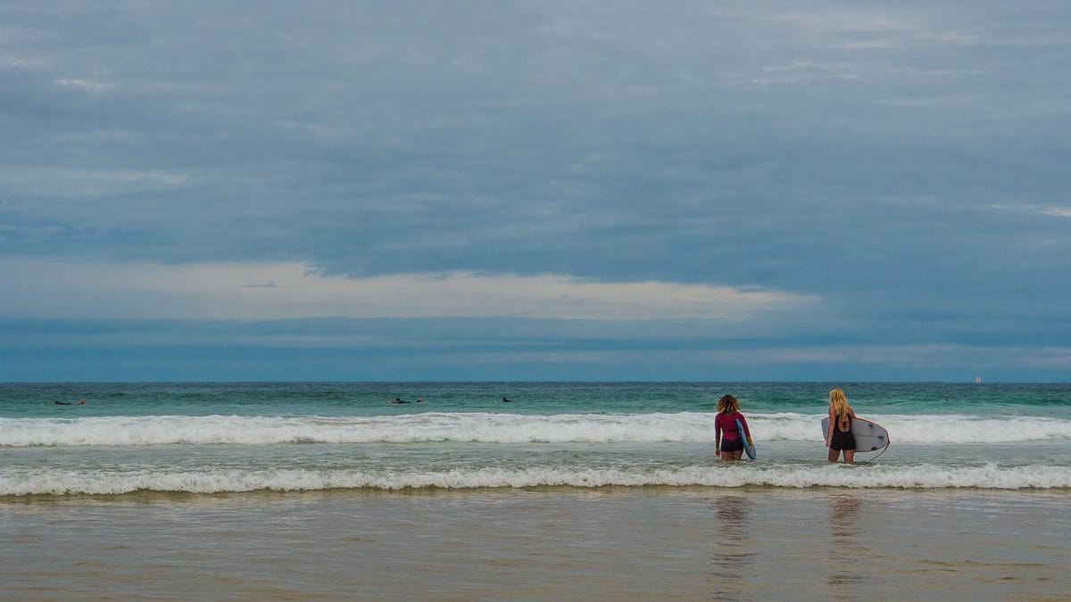 Surferinnen an einem Strand im Baskenland