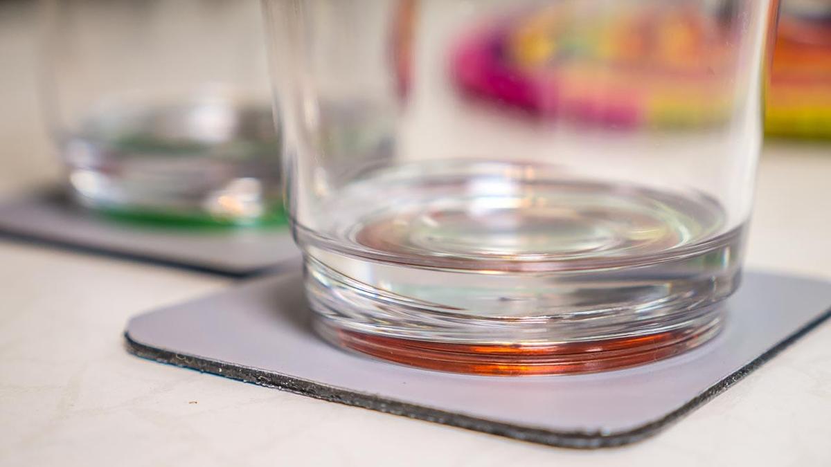 Ein Wasserglas mit buntem Boden auf einem Magnetuntersetzer der das Glaeser verrutschen verhindert