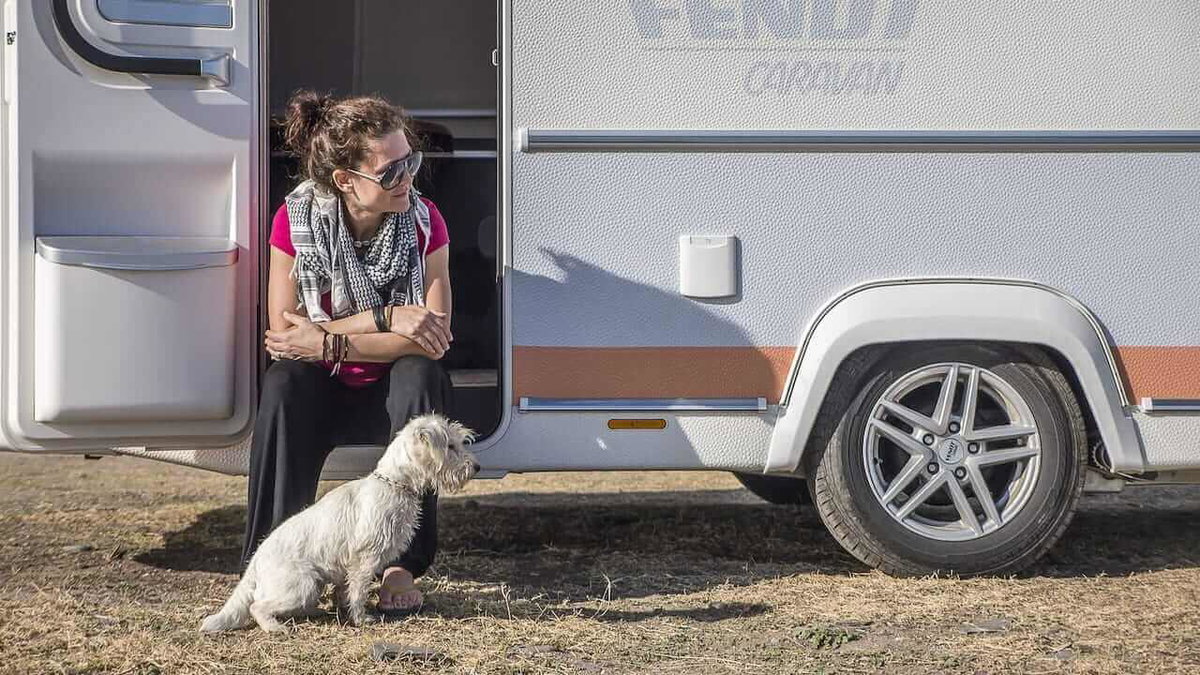 Ein Hund mit seinem Frauchen vor einem Wohnwagen