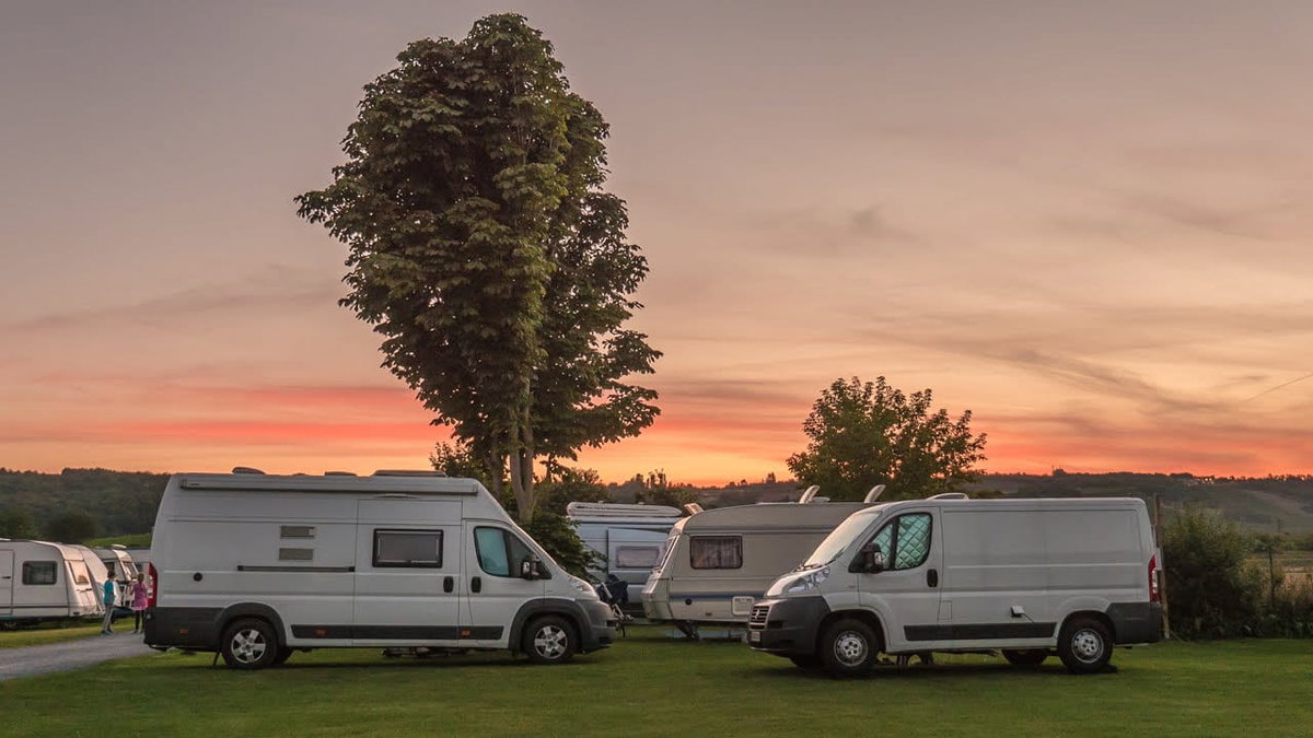 Wohnmobile auf einem Campingplatz bei Sonnenuntergang