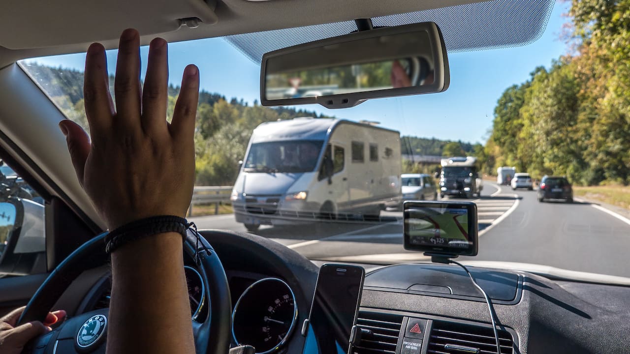 Ein Mann beim Wohnmobil gruessen auf der Strasse