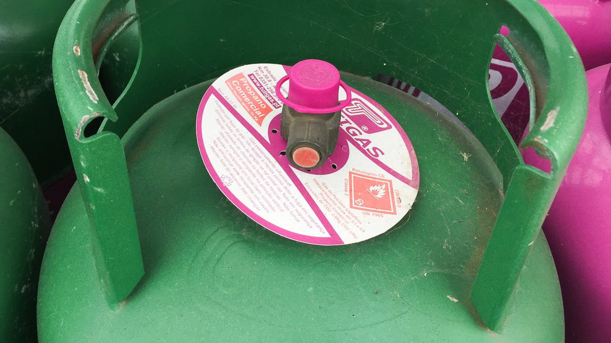 Eine gruene Gasflasche in Portugal mit rosa Ventil