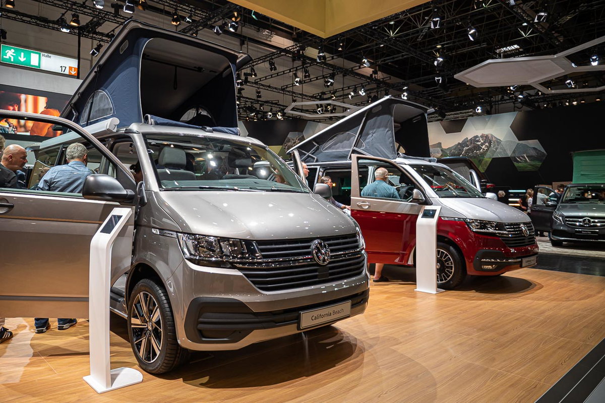 Blick von vorn auf einen VW California 6.1 Beach mit offenen Türen und aufgestelltem Hochdach auf dem Messestand des Caravan Salon 2019 in Düsseldorf