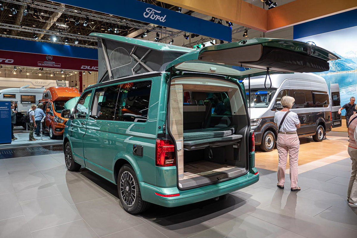 Blick von hinten auf einen VW California 6.1 Coast mit offener Heckklappe und aufgestelltem Hochdach auf dem Messestand des Caravan Salon 2019 in Düsseldorf