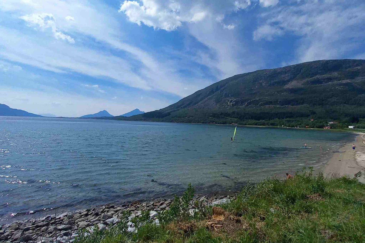 Bucht mit Sandstrand und Blick auf die umliegenden Berge direkt am Küstenweg.
