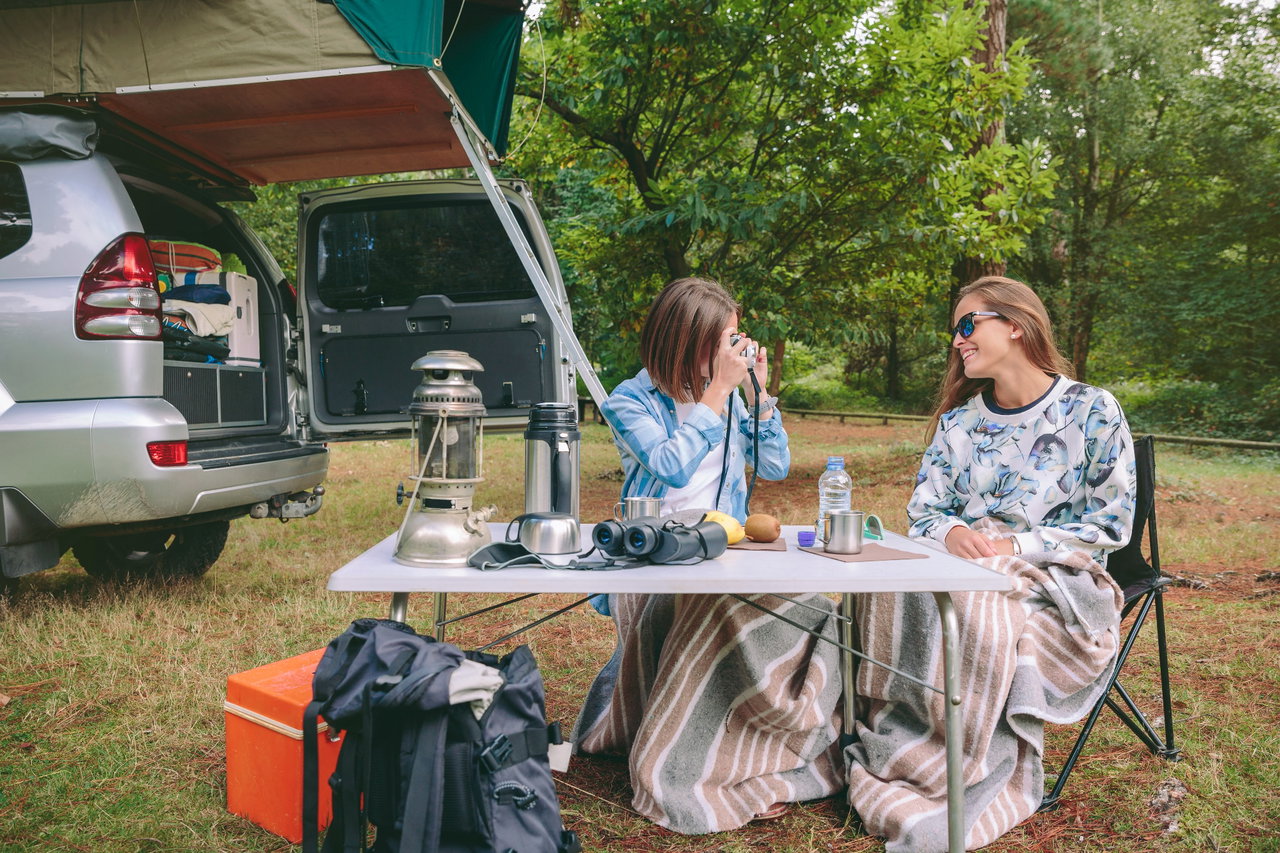 10 Dinge, die du beim Camping unbedingt dabei haben solltest - Campingtisch Campingstühle Natur Kühlbox Dachzelt