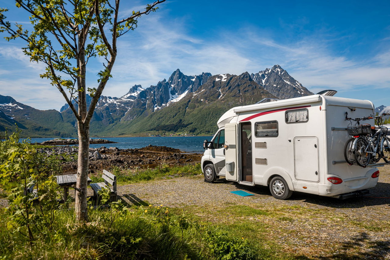 Wohnmobil steht am See umgeben von Bergen in einer schönen Landschaft.