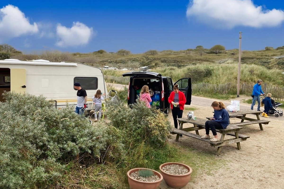 Checkliste: Camping mit Kind - Familie vor Wohnwagen auf Campingplatz