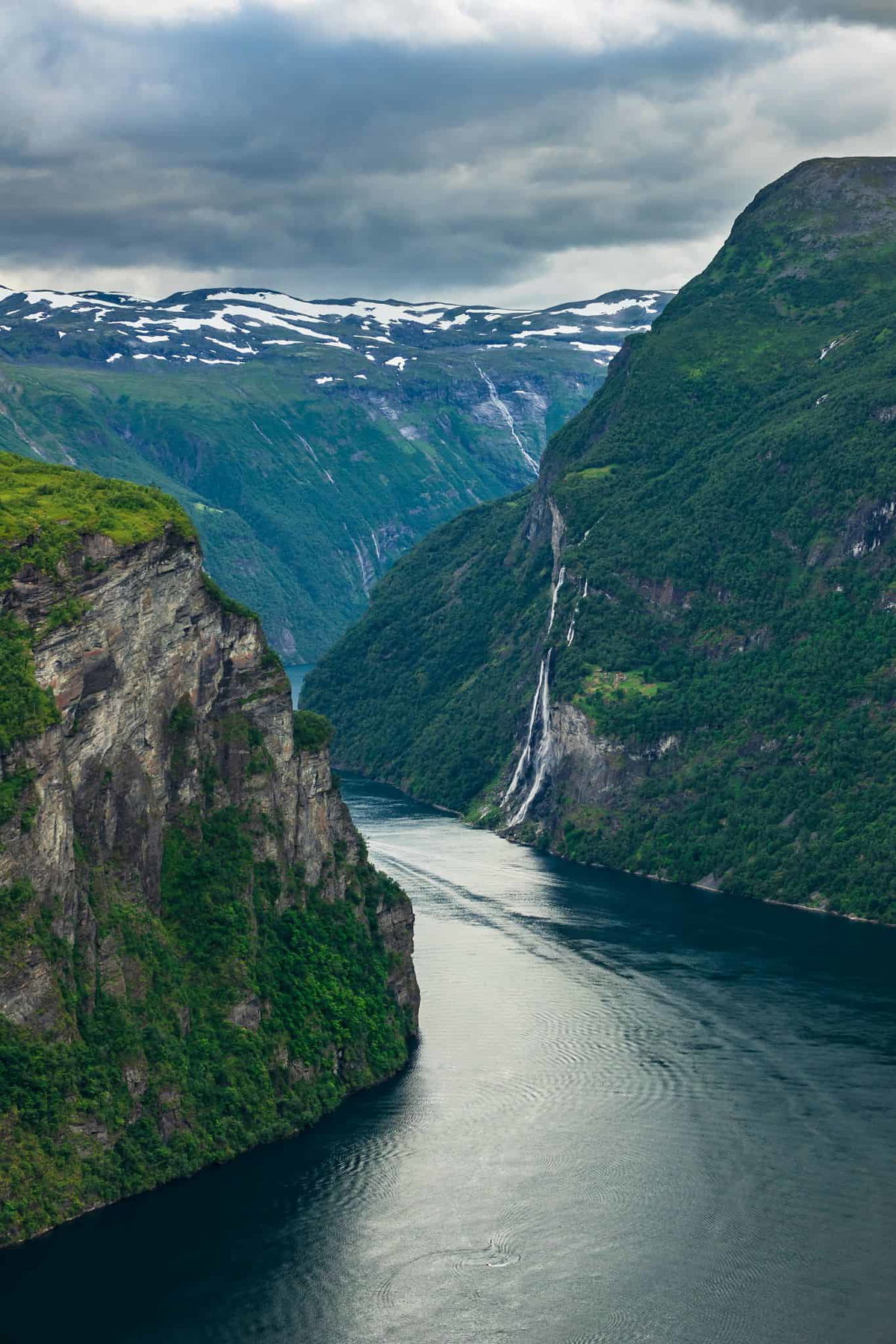 Alternativer Text: Atemberaubende Fjordlandschaft in Norwegen mit Wasserfällen und grünen Bergen.