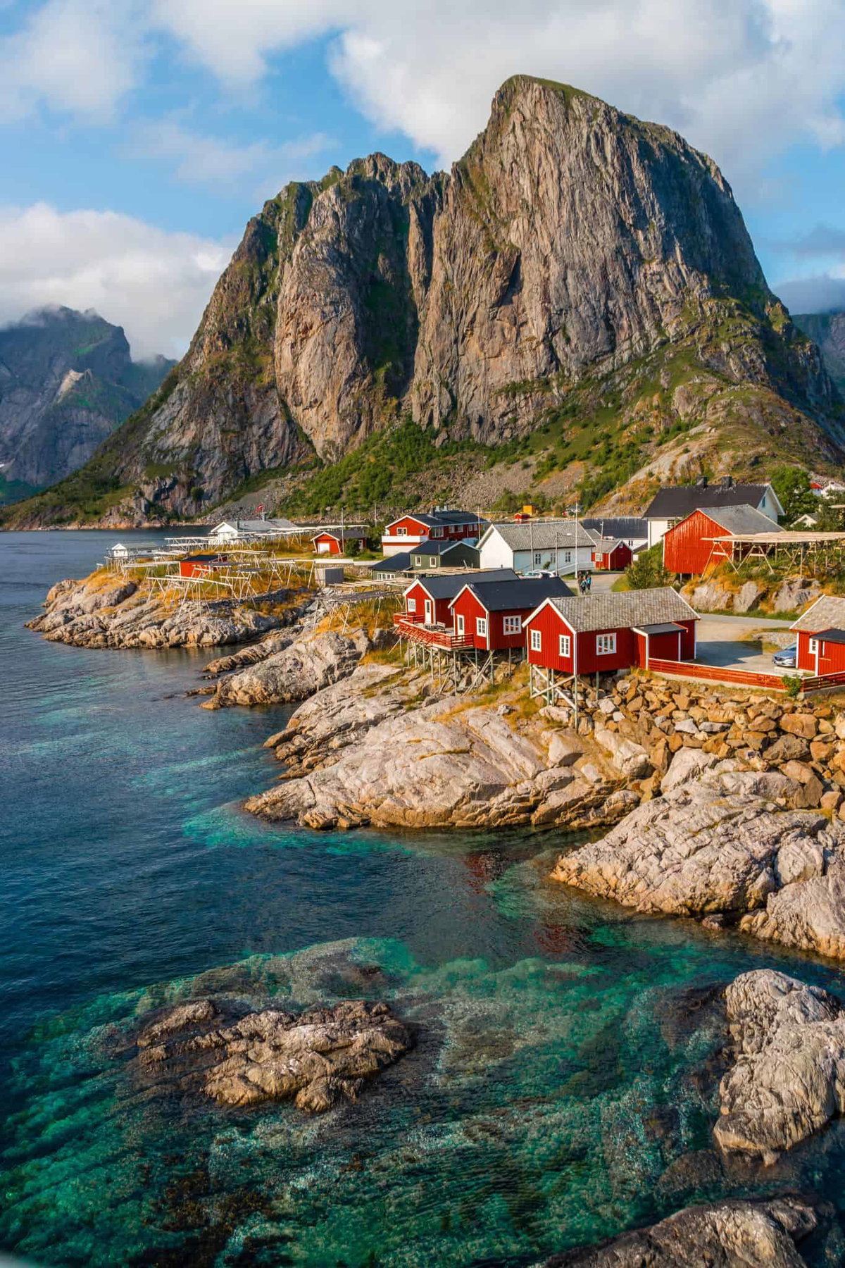 Bunte norwegische Fischerhäuser direkt am Wasser vor beeindruckender Bergkulisse.