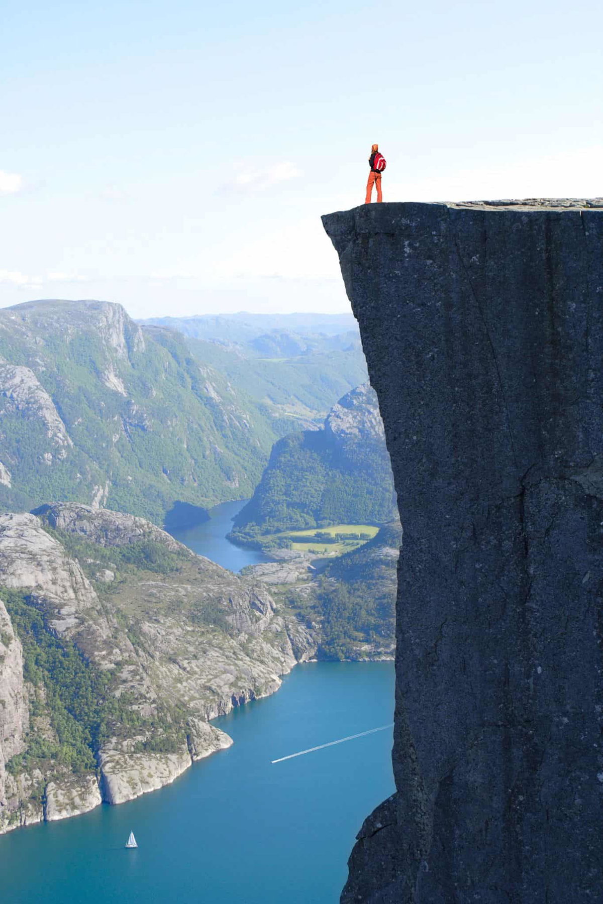 Wanderer auf einer hohen Klippe mit Blick auf Fjord, Natur, Abenteuer.